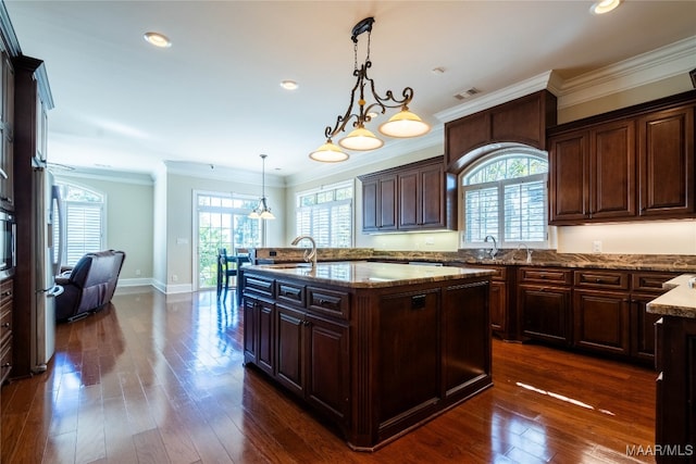 kitchen with a kitchen island with sink, decorative light fixtures, plenty of natural light, and dark hardwood / wood-style flooring