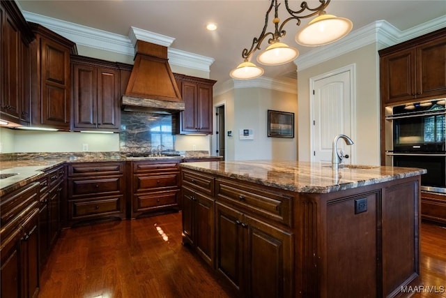 156 Walnut Point Dr, Wetumpka, AL 36093 - kitchen featuring stainless steel double oven, a kitchen island with sink, a sink, dark wood-style floors, and premium range hood