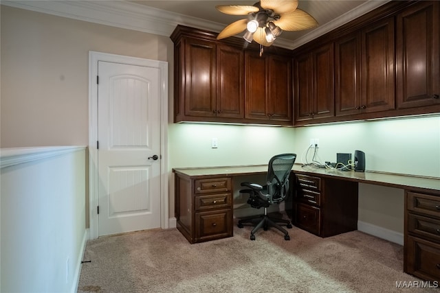 carpeted office with built in desk, crown molding, and ceiling fan