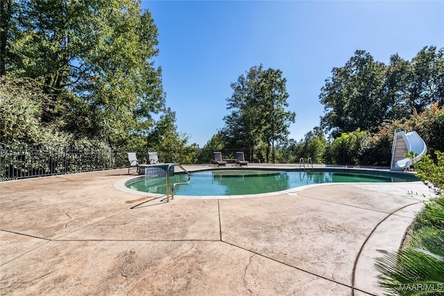 view of swimming pool with a patio and a water slide