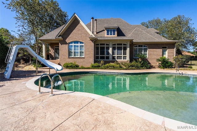 view of swimming pool with a patio and a water slide