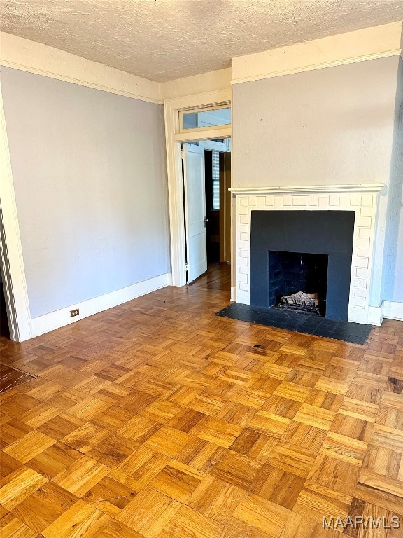 unfurnished living room featuring a brick fireplace, light parquet flooring, and a textured ceiling