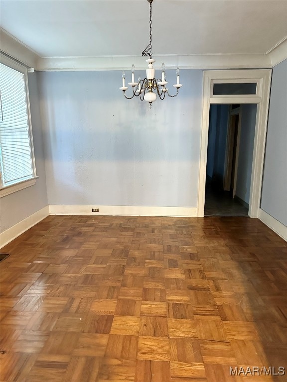 unfurnished dining area with parquet flooring, crown molding, and a notable chandelier