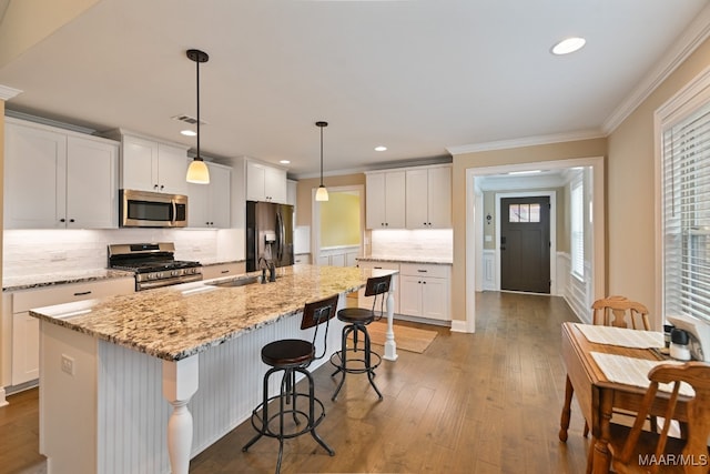 kitchen featuring appliances with stainless steel finishes, white cabinets, hardwood / wood-style floors, and a kitchen island with sink