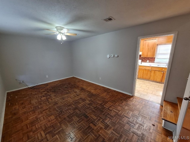 unfurnished room with ceiling fan, sink, and dark parquet flooring