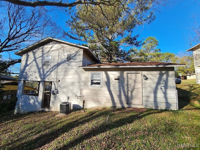 back of house with central air condition unit and a yard