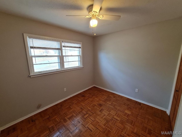 empty room with dark parquet floors and ceiling fan