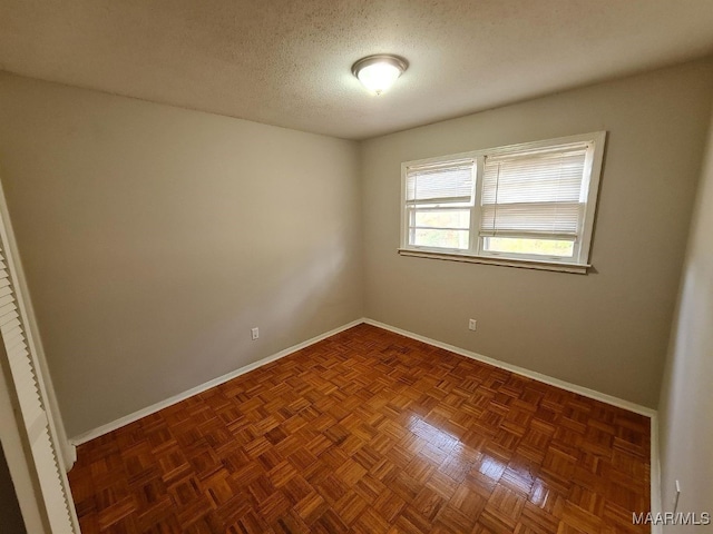 empty room featuring a textured ceiling and baseboards
