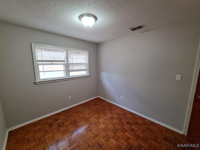 empty room with dark parquet floors and a textured ceiling