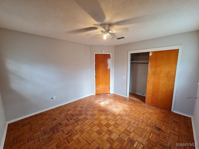 unfurnished bedroom featuring a closet, a ceiling fan, visible vents, baseboards, and a textured ceiling