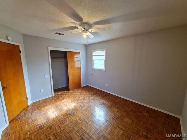 unfurnished bedroom featuring parquet flooring, a textured ceiling, and ceiling fan