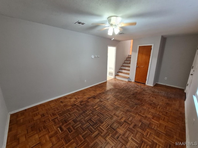 empty room featuring a ceiling fan, visible vents, stairs, and baseboards