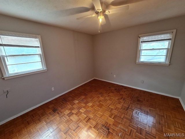 empty room featuring parquet floors, a healthy amount of sunlight, and ceiling fan