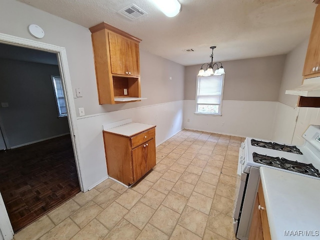 kitchen with white gas range, exhaust hood, hanging light fixtures, a notable chandelier, and a textured ceiling