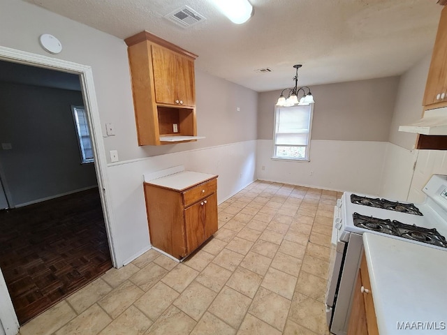 kitchen featuring visible vents, light countertops, white range with gas stovetop, under cabinet range hood, and an inviting chandelier