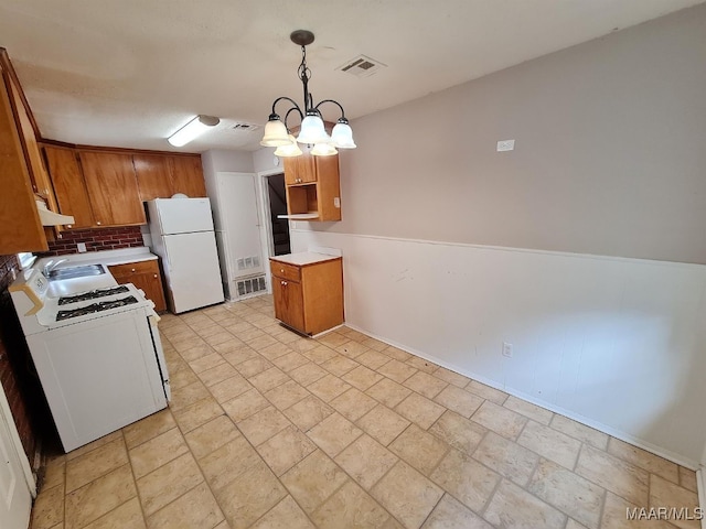 kitchen featuring white appliances, decorative backsplash, a chandelier, and hanging light fixtures