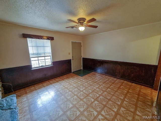 empty room featuring wooden walls, a textured ceiling, and ceiling fan