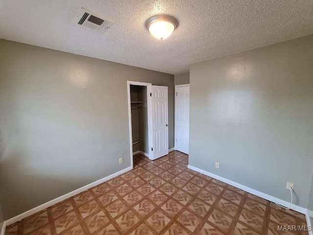 unfurnished bedroom with a closet, a textured ceiling, and a walk in closet