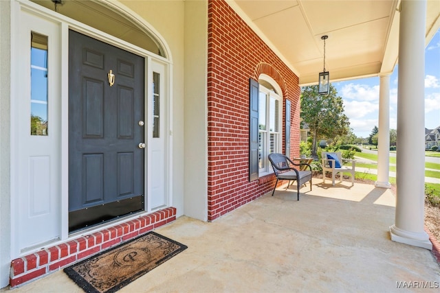 doorway to property featuring french doors, a porch, and brick siding