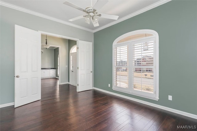 empty room with crown molding, dark wood-style flooring, a ceiling fan, and baseboards