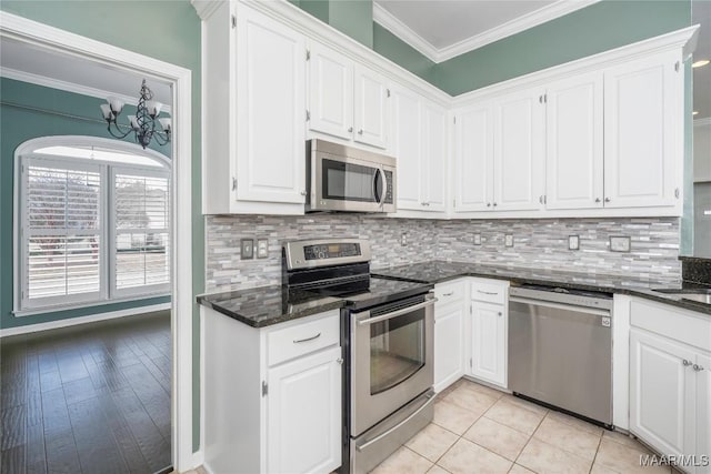 kitchen with stainless steel appliances, white cabinetry, crown molding, and backsplash