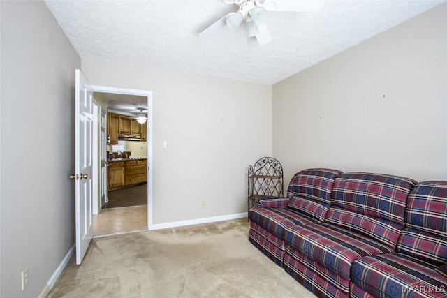 living area featuring a textured ceiling, light colored carpet, and ceiling fan