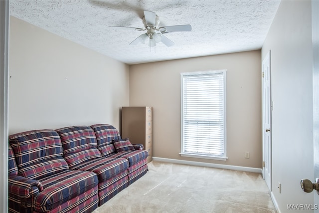 sitting room with light carpet, a textured ceiling, and ceiling fan