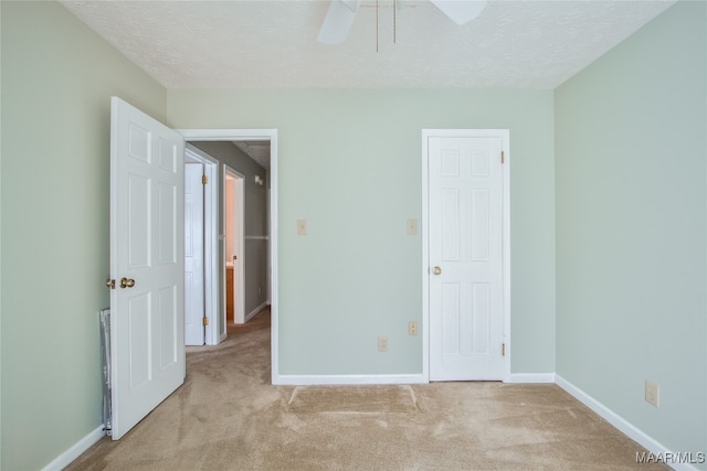 empty room with a textured ceiling, light colored carpet, and ceiling fan