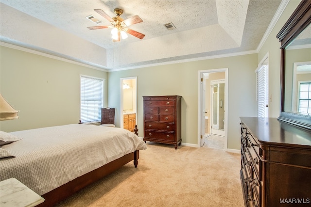 bedroom with connected bathroom, light carpet, a raised ceiling, and multiple windows