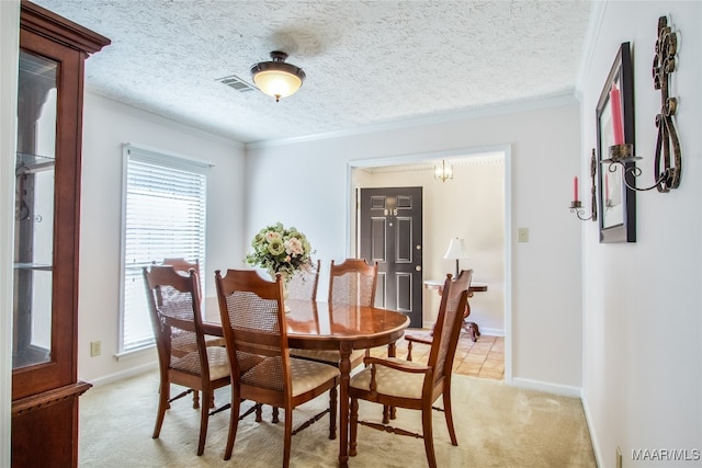 dining room featuring ornamental molding, light colored carpet, and a textured ceiling