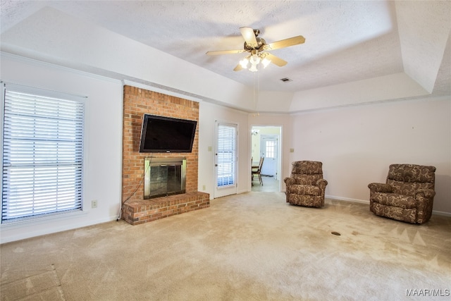 unfurnished room featuring a fireplace, ceiling fan, carpet flooring, and a raised ceiling