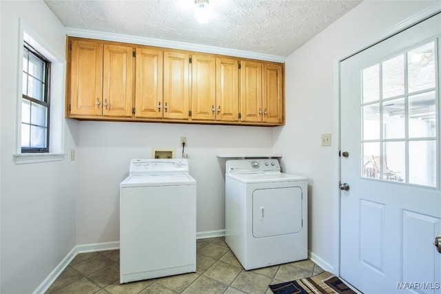 clothes washing area with a textured ceiling, cabinets, plenty of natural light, and washing machine and clothes dryer