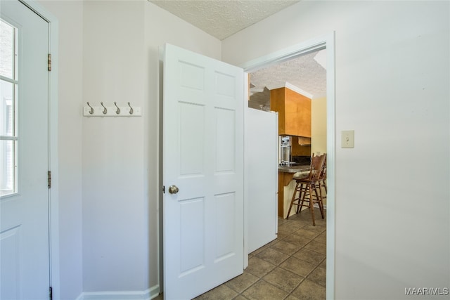 corridor with a textured ceiling, light tile patterned flooring, and plenty of natural light