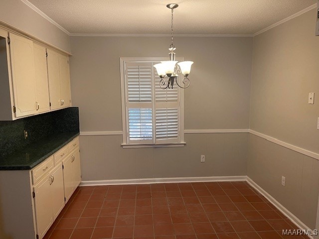 kitchen with a textured ceiling, wooden walls, white cabinets, crown molding, and an inviting chandelier