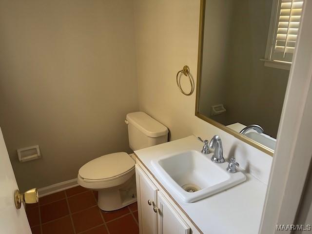 half bath featuring baseboards, tile patterned floors, vanity, and toilet