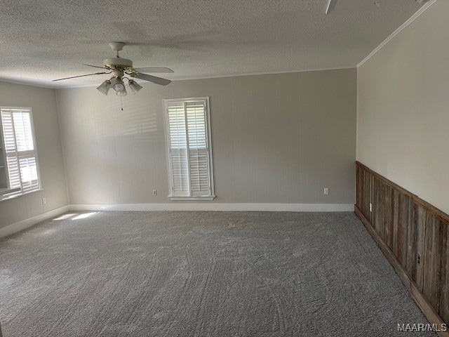 empty room with carpet flooring, ornamental molding, a textured ceiling, and ceiling fan