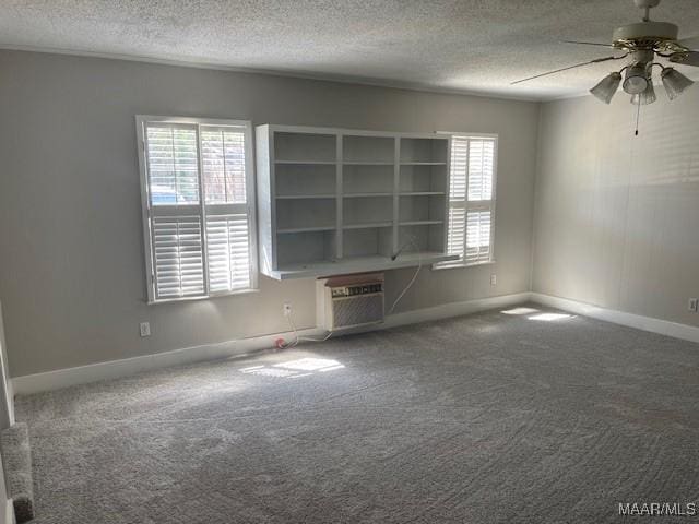 empty room featuring a textured ceiling, a healthy amount of sunlight, a ceiling fan, and baseboards