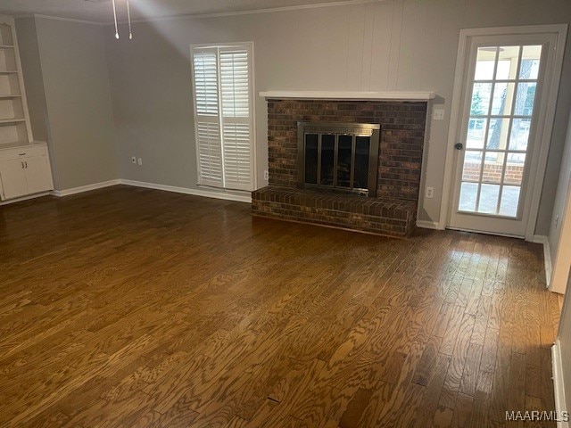 unfurnished living room featuring ornamental molding, a brick fireplace, dark hardwood / wood-style floors, and ceiling fan