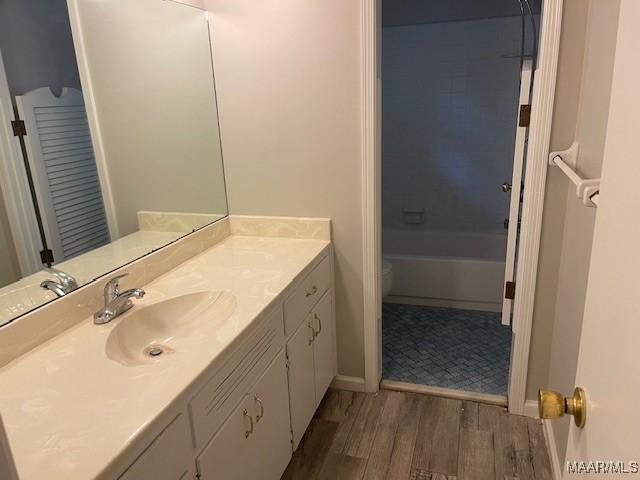 full bathroom featuring toilet, wood finished floors, vanity, bathtub / shower combination, and baseboards