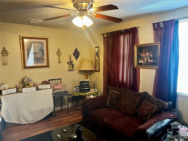 living room featuring a textured ceiling, wood-type flooring, and ceiling fan