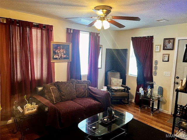 living room with ceiling fan, wood-type flooring, and a textured ceiling