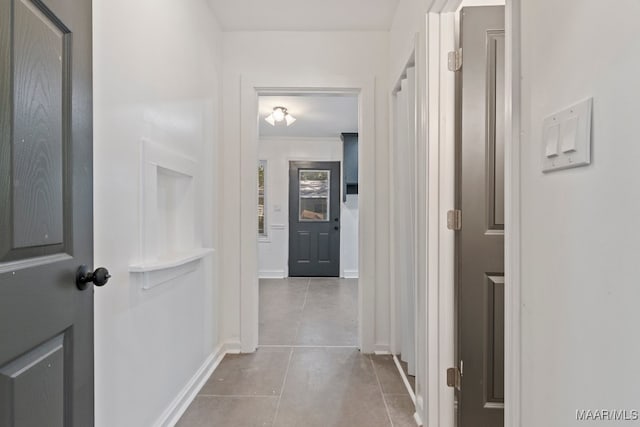 hallway featuring crown molding and light tile patterned floors