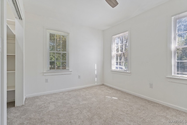 spare room with a healthy amount of sunlight, light colored carpet, and ceiling fan