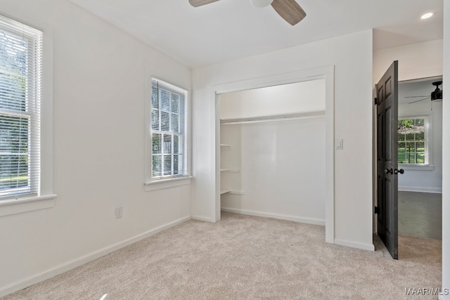 unfurnished bedroom featuring light carpet, multiple windows, and ceiling fan