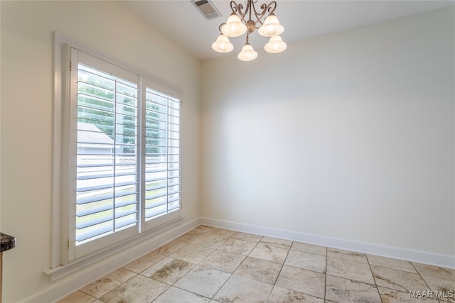 empty room featuring a healthy amount of sunlight and a chandelier