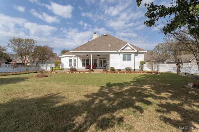 back of property with ceiling fan and a yard