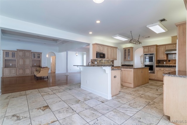 kitchen featuring a kitchen island, backsplash, a kitchen bar, stainless steel double oven, and light brown cabinets