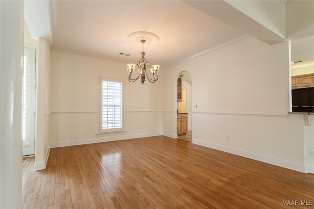 empty room with crown molding, wood-type flooring, and a notable chandelier