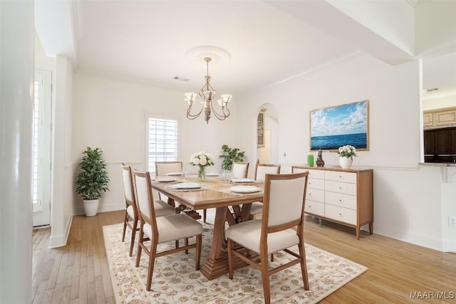 dining room with crown molding, an inviting chandelier, and light hardwood / wood-style floors