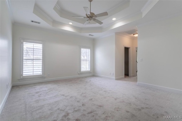 carpeted spare room featuring crown molding, a wealth of natural light, and a tray ceiling